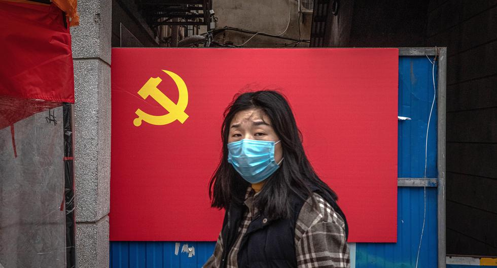 Una mujer con una máscara facial protectora camina por una zona residencial de Wuhan la ciudad china donde se inició la pandemia de coronavirus. (EFE/EPA/ROMAN PILIPEY)