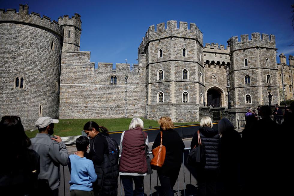 La gente se reunió frente a la entrada del Castillo de Windsor en Windsor, al oeste de Londres, el 17 de abril de 2021, antes del funeral del príncipe Felipe de Gran Bretaña, duque de Edimburgo. (Tolga Akmen / AFP).
