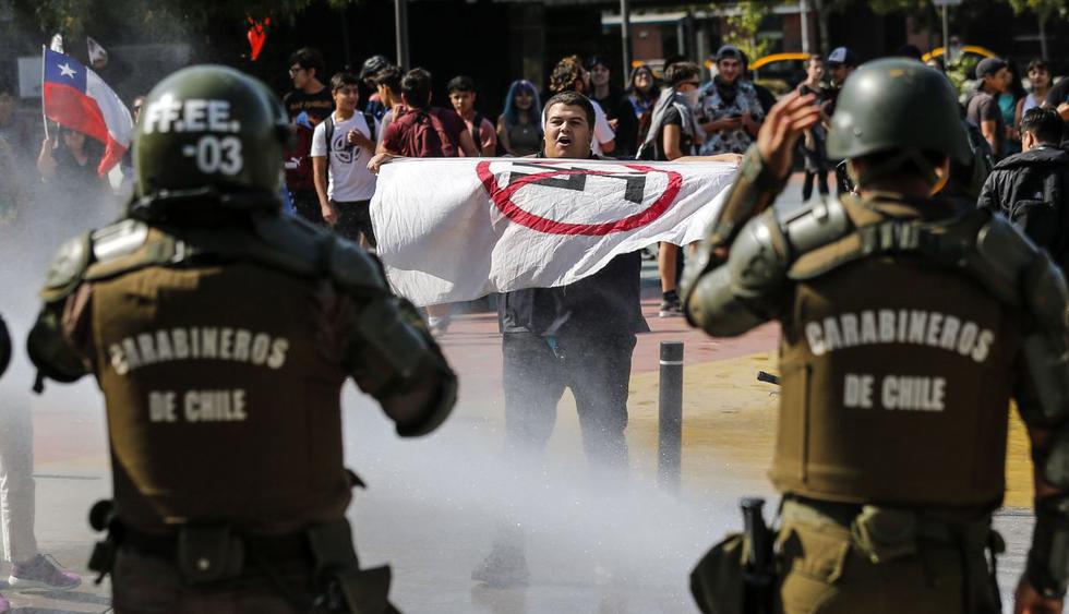 Un tenso encontrón protagonizaron este sábado dos grupos de manifestantes en Santiago de Chile. Algunos con una fotografía de Pinochet en brazos gritaron contra una nueva Constitución, en sentido opuesto a los que pedían su aprobación. (AFP).