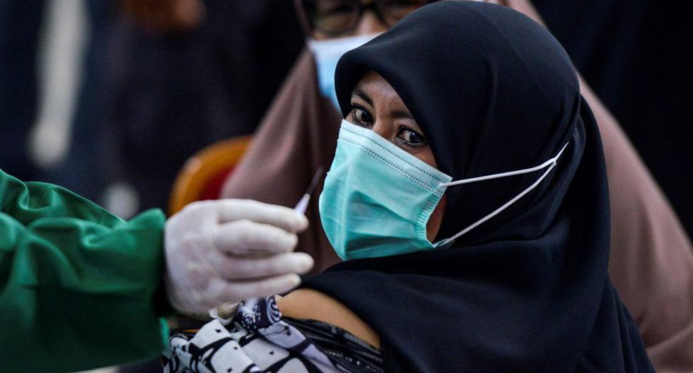 Una mujer observa una dosis de la vacuna Sinovac contra el coronavirus Covid-19 durante una vacunación masiva en Sibreh, provincia de Aceh, Indonesia. (Foto de CHAIDEER MAHYUDDIN / AFP).
