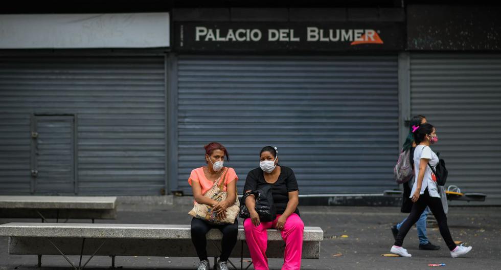 Las personas usan máscaras faciales mientras descansan en el bulevar de Sabana Grande, en Caracas. (AFP / Federico PARRA).