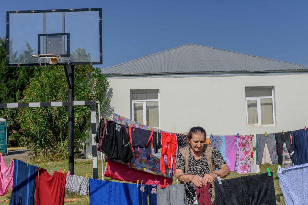 Fatma Suleymanova, una refugiada de 80 años que huyó de Terter debido al conflicto militar en curso entre Armenia y Azerbaiyán sobre la región separatista de Nagorno-Karabaj, cuelga ropa en una cuerda en el jardín de una escuela secundaria en la ciudad de Barda. (AFP/Bulent Kilic).