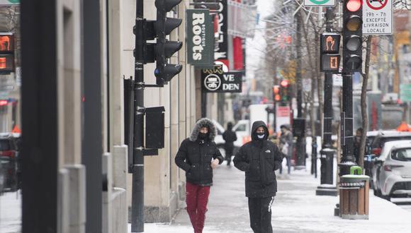 Las personas usan máscaras faciales mientras caminan por la calle Sainte-Catherine en el Boxing Day en Montreal. (Graham Hughes / The Canadian Press vía AP)