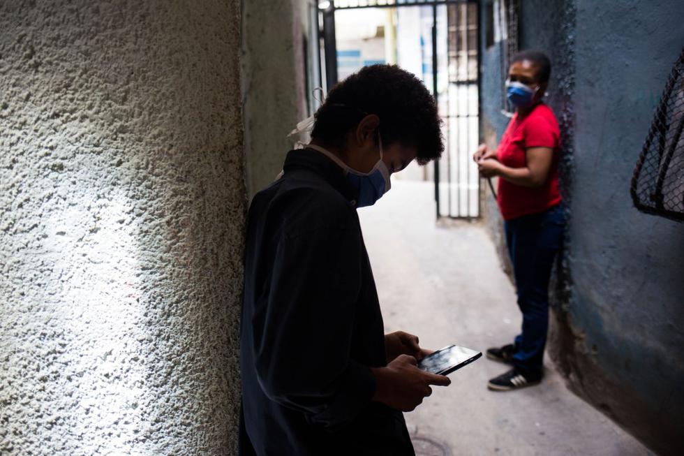 Jonathán  Figueroa, de 14 años, es visto usando su teléfono celular en el barrio Bello Campo en Chacao, Caracas. (AFP / Cristian Hernandez).