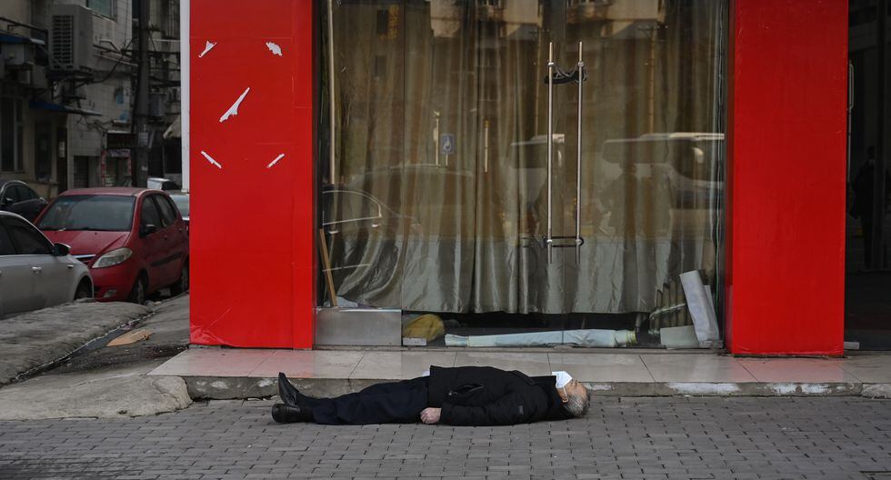 Hombre tendido en el suelo en China (Foto: AFP/Héctor Retamal)
