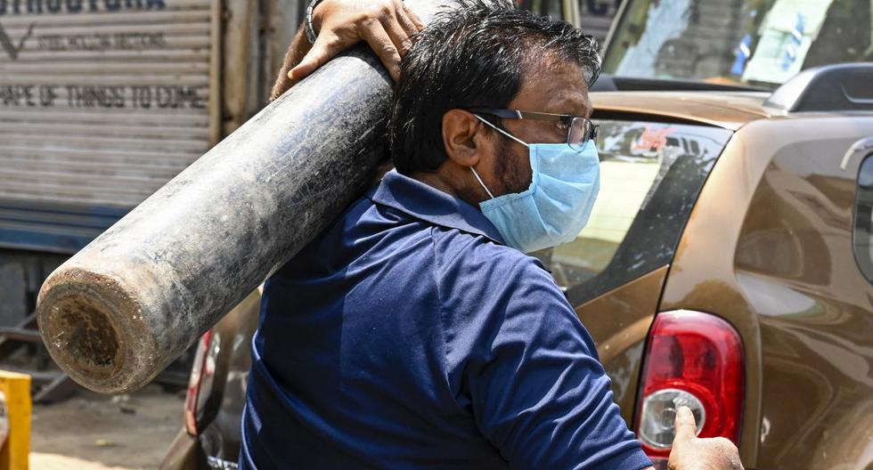Un hombre lleva un cilindro de oxígeno cuando llega para recargarlo para un paciente con coronavirus en un centro de recarga en Nueva Delhi, el 5 de mayo de 2021. (Tauseef MUSTAFA / AFP).