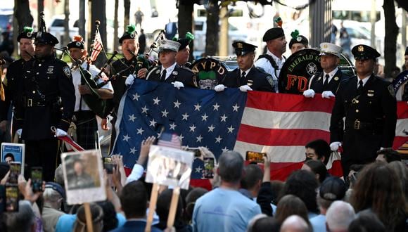 La policía y los bomberos de Nueva York sostienen una bandera de los EE. UU. durante una ceremonia que conmemora el 20 aniversario de los ataques del 11 de septiembre en el World Trade Center, en Nueva York.  (Foto: Jim WATSON / AFP)
