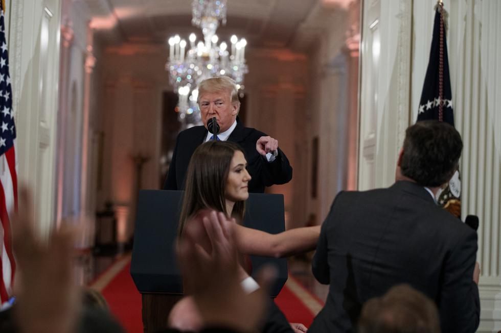 El presidente Donald Trump observa cómo un asistente de la Casa Blanca se acerca para quitarle un micrófono al periodista de la CNN Jim Acosta durante una conferencia de prensa en la Casa Blanca. (AP)