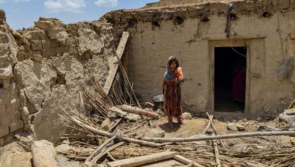 Un niño se encuentra junto a una casa dañada por un terremoto en el distrito de Bermal, provincia de Paktika, el 23 de junio de 2022. (Foto de Ahmad SAHEL ARMAN / AFP)