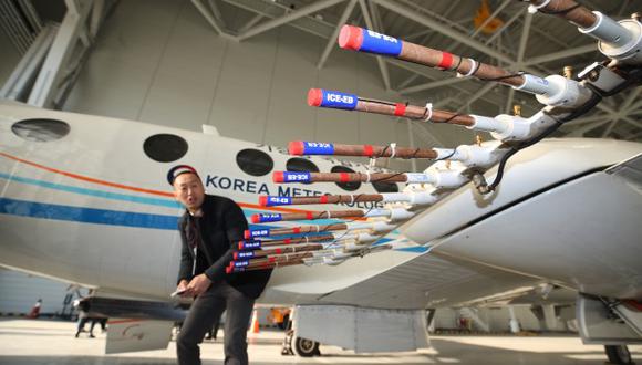 Un hombre mirando un avión de la Administración Meterológica de Corea listo para dispersar el yoduro de plata, un compuesto que se cree causa la lluvia, en una percha en el aeropuerto de Gimpo en Seúl. (Foto: AFP)