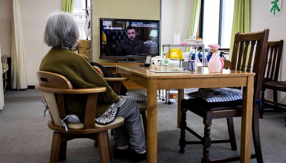 Una anciana mira la televisión que muestra un informe de noticias del presidente ucraniano Volodymyr Zelensky, en una guardería para personas mayores en Tokio el 6 de abril de 2022. (Foto de Behrouz MEHRI / AFP)