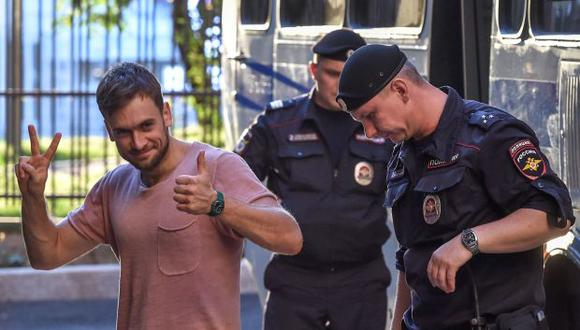Piotr Verzilov gesticula mientras camina con la policía durante una audiencia en un tribunal en Moscú luego de invadir el campo de fútbol del estadio sede de la final del Mundial Rusia 2018. (Foto: AFP)