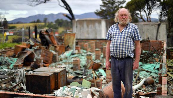 Esta imagen, tomada el pasado de mayo de 2020, muestra a Wayne Keft, de 66 años, parado frente a las ruinas de su casa destruidas durante los incendios forestales cerca de Cobargo, una ciudad en la costa sur del estado de Nueva Gales del Sur. Las víctimas de los catastróficos incendios forestales de Australia todavía viven en tiendas de campaña, garajes y refugios improvisados expuestos a la pandemia del COVID-19. (Saeed KHAN / AFP)