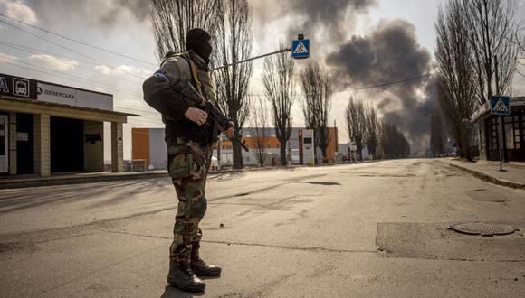 Un militar ucraniano hace guardia cerca de un almacén en llamas alcanzado por un proyectil ruso en los suburbios de la capital, Kiev, el 24 de marzo de 2022. (Foto de FADEL SENNA / AFP)