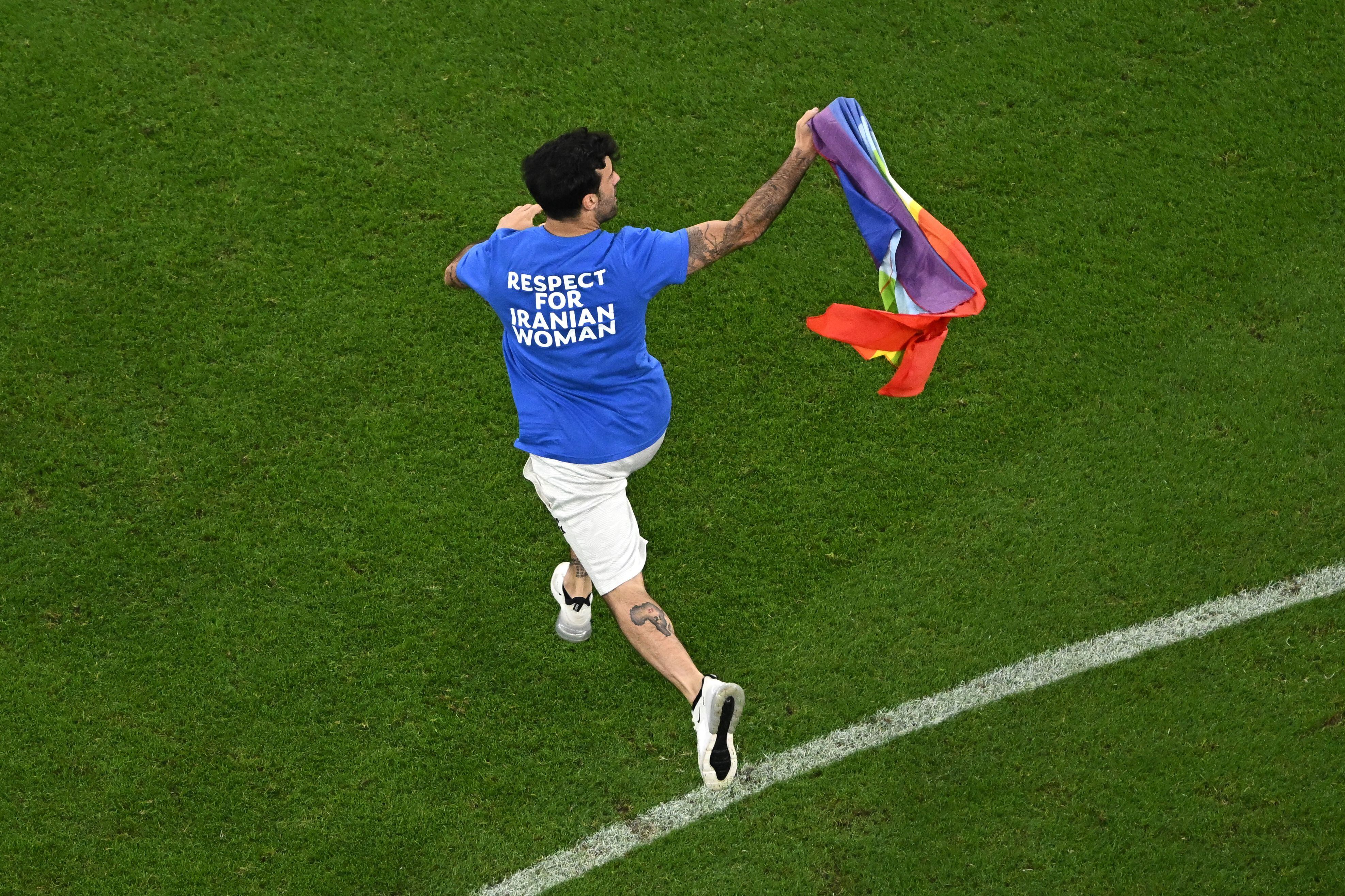 Un hombre invade el campo con una bandera LGBT mientras usa una camiseta que dice "Respeto a la mujer iraní" durante el partido de fútbol del Grupo H de la Copa Mundial Qatar 2022 entre Portugal y Uruguay en el Estadio Lusail en Lusail, al norte de Doha el 28 de noviembre. , 2022. (Foto de MANAN VATSYAYANA / AFP)