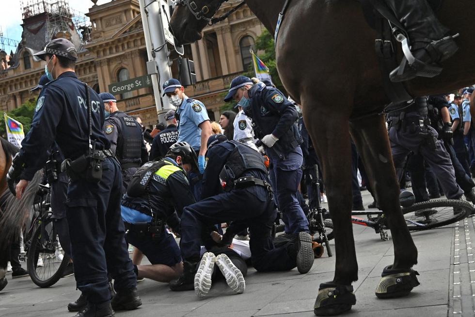 La policía detiene a un manifestante durante una manifestación antibloqueo en Sydney mientras miles de personas se reunían para manifestarse contra las órdenes de hace una nueva cuarentena en la ciudad. (Foto de Steven SAPHORE / AFP)