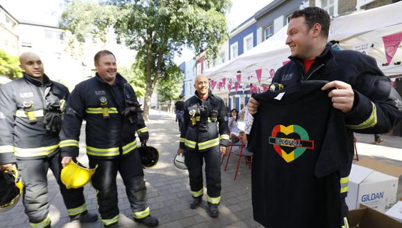 Los bomberos compran camisetas de Grenfell con fines benéficos en Portobello Road en Kensington, no lejos de los restos de la Torre Grenfell, en Londres el 25 de agosto de 2017 antes del Carnaval de Notting Hill. (Foto de Tolga AKMEN / AFP)