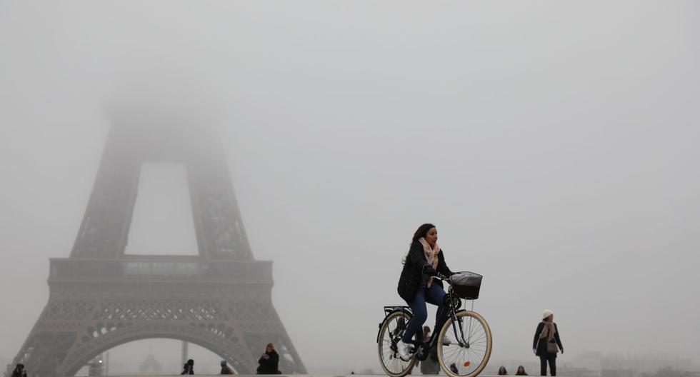 Las personas andan en bicicleta y scooter eléctrico cerca de la Torre Eiffel que se ve parcialmente oculta por la niebla. El monumento está cerrado al público debido a una huelga nacional contra los planes del gobierno para un sistema de pensiones "universal" que dicen que será obligar a millones de personas a trabajar más tiempo. (AFP)