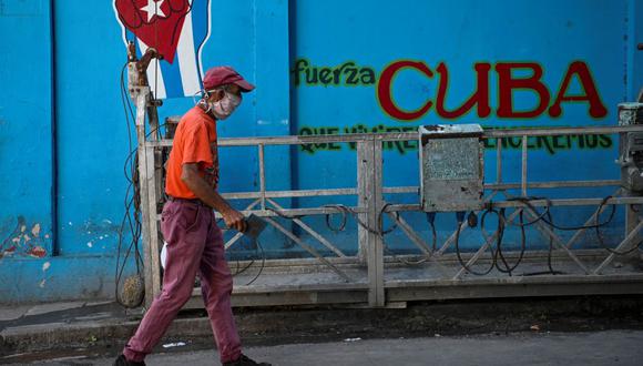 Un anciano con mascarilla pasa junto a un grafiti con la bandera cubana en La Habana, el 11 de agosto de 2021. (Foto de YAMIL LAGE / AFP)