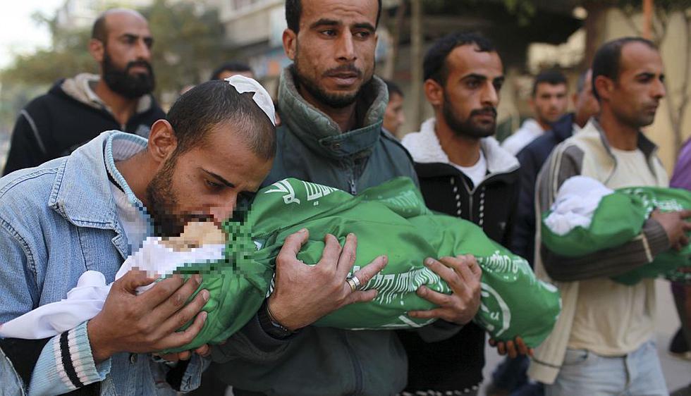 Hombre palestino besa a uno de sus hijos en su funeral en el norte de Gaza. Producto de los ataques murieron  Stefan 18 meses y Tamer de 3 años.