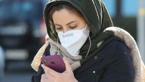 An Iranian woman wearing a protective mask checks a message on her smart phone in the Iranian capital Tehran on March 2, 2020, following the COVID-19 illness outbreak, which Iran says has claimed 66 lives out of 1,501 cases of infection in the Islamic republic since February. - The novel coronavirus has sparked intense debate in Iran between ultra-conservative Shiite clerics and the government on how to most effectively tackle the deadliest outbreak of the disease outside China. (Photo by ATTA KENARE / AFP)