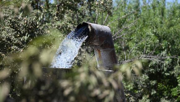 El agua bombeada de un pozo subterráneo fluye hacia una cisterna en una granja en Fresno, California, el 24 de julio de 2021. (Foto de Robyn Beck / AFP)