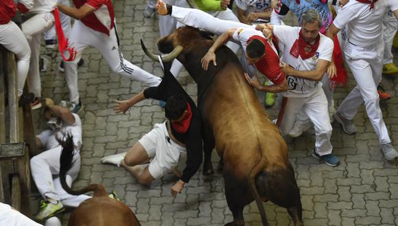 Los participantes caen junto a los toros de José Cebada Gago durante el quinto "encierro" (corrida de toros) de las fiestas de San Fermín en Pamplona, ​​norte de España, el 11 de julio de 2022. (Foto de ANDER GILLENEA / AFP)