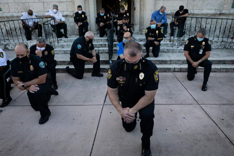 Oficiales de policía se arrodillan durante una manifestación en Coral Gables, Florida, en respuesta a la reciente muerte de George Floyd, un hombre negro desarmado que murió mientras era arrestado y sujetado al suelo por un oficial de policía de Minneapolis. (AFP / Eva Marie UZCATEGUI)