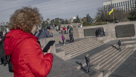 La gente se reúne en un lugar alto en busca de un lugar con una mejor señal móvil de roaming ruso en el recién liberado Kherson el 14 de noviembre de 2022, en medio de la invasión rusa de Ucrania. (Foto de BULENT KILIC / AFP)