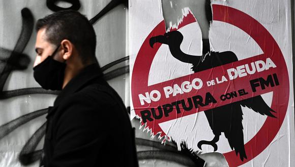 Un hombre pasa junto a una señal contra el pago de la deuda con el FMI pegado en una tienda en alquiler durante el cierre impuesto por el gobierno contra la propagación del nuevo coronavirus, en Buenos Aires. (Foto: AFP/JUAN MABROMATA)