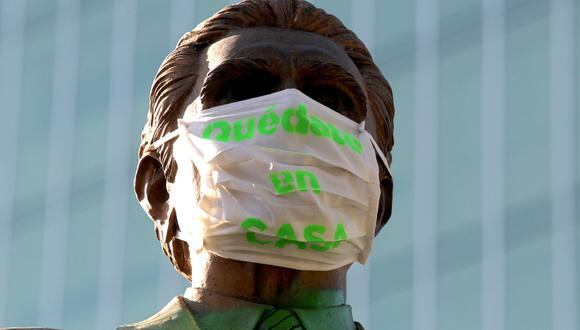 Una estatua en México lleva na máscara que dice "quédate en casa" por la pandemia del coronavirus. (Foto: AFP/Ulises Ruiz)