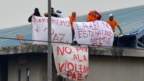 Reclusos sostienen carteles en lo alto de un techo en el penal Regional 8. (Foto: Fernando Mendez / AFP)