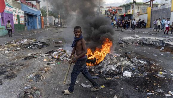 En esta foto de archivo tomada el 10 de octubre de 2022, un hombre pasa junto a una barricada en llamas durante una protesta contra el primer ministro haitiano Ariel Henry que pide su renuncia, en Puerto Príncipe, Haití. (Foto de Richard Pierrin / AFP)
