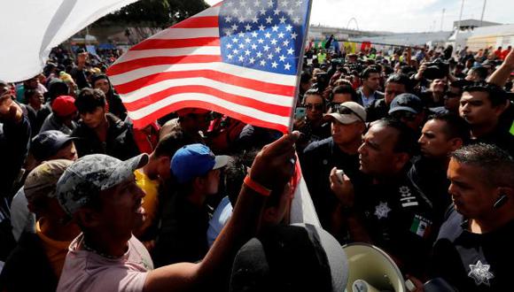 Un migrante, parte de una caravana de miles de personas que viajan desde América Central hacia Estados Unidos, tiene una bandera de los Estados Unidos mientras migrantes negocia con policías mexicanos. (Foto: Reuters)
